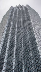 Vertical view of a towering skyscraper with a distinctive glass facade pattern.